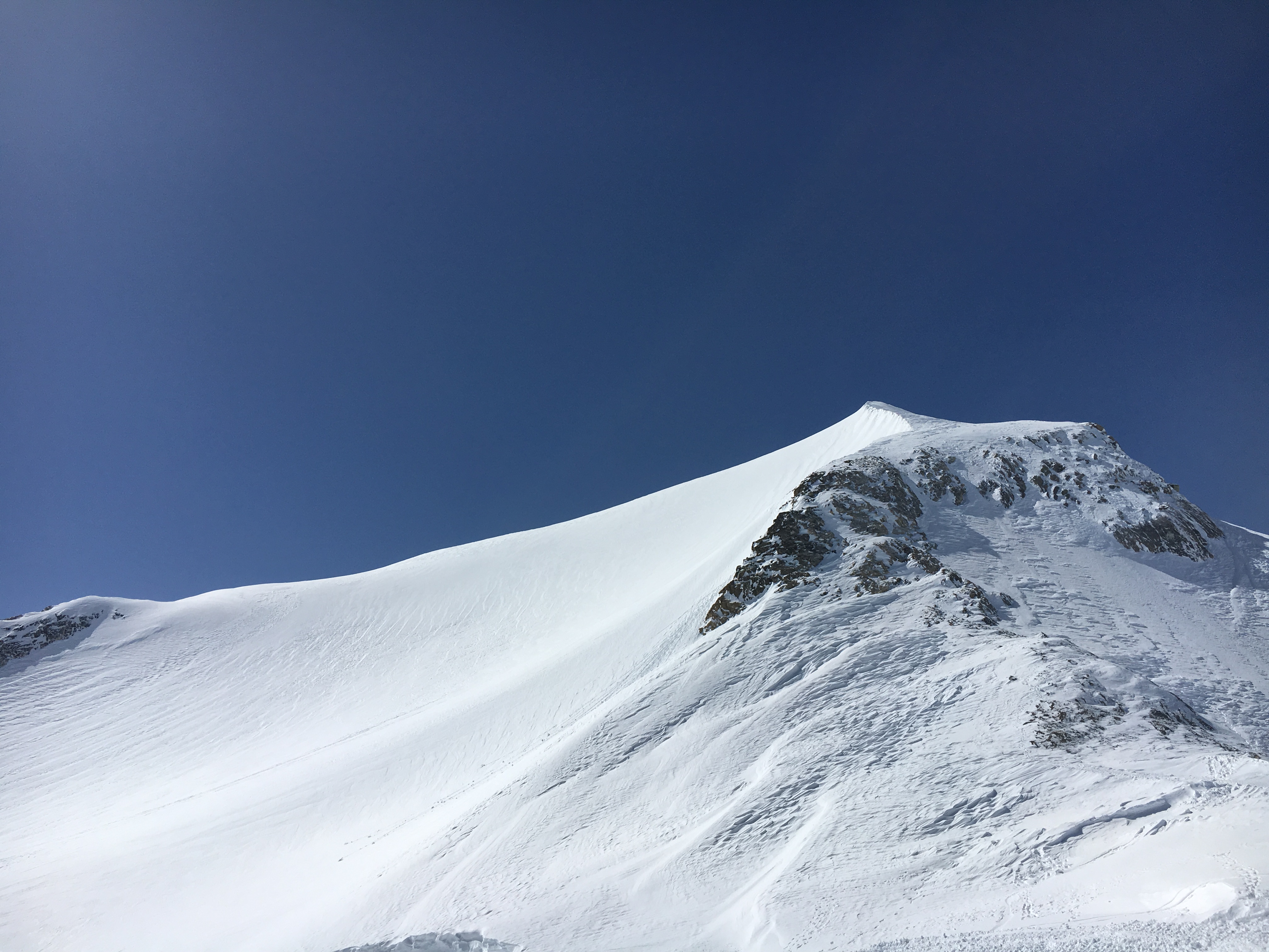A snow-covered mountain crest under shifting cloud